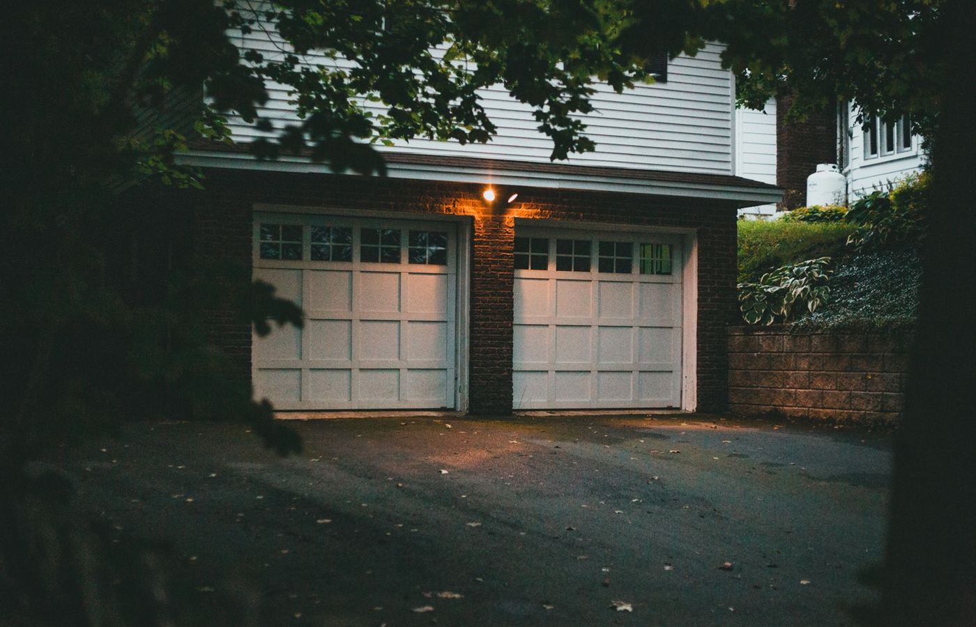 Two white residential garage doors lit in the evening