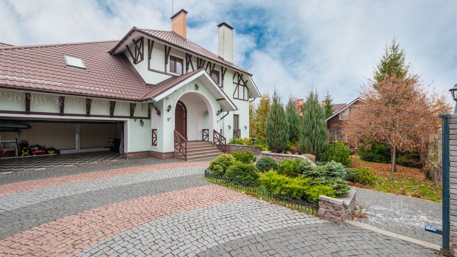 Home with a garage and brick driveway on a bright day