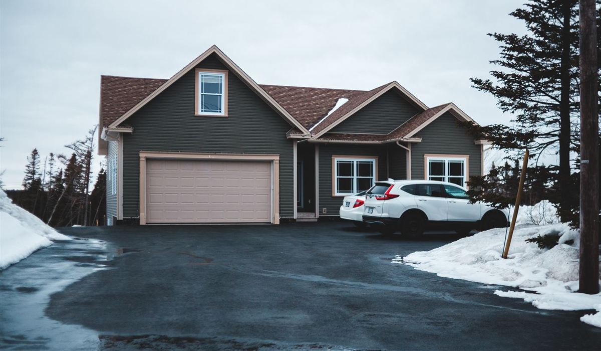 Home with an attached garage on a snowy winter driveway