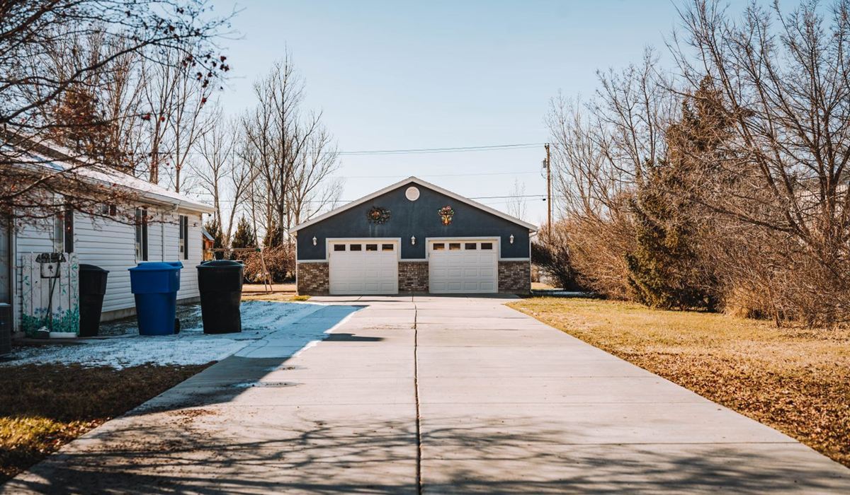 Detached residential garage with a wide driveway on a bare winter day