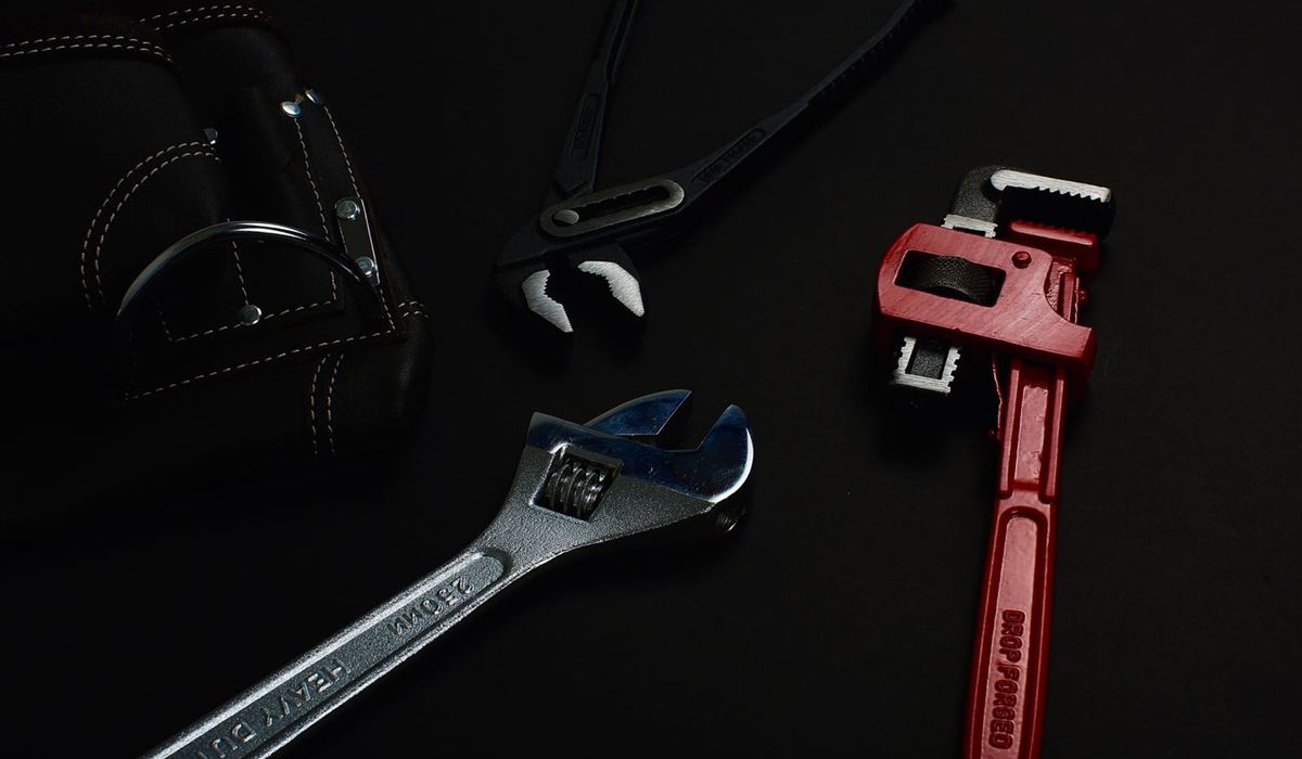 Adjustable wrench and pipe wrench laid out for a repair job